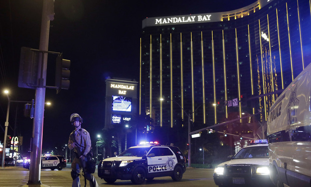 In this Sunday, Oct. 1, 2017 file photo, police officers stand along the Las Vegas Strip near the Mandalay Bay resort and casino during a shooting at a country music festival, in Las Vegas. Jay Purves and his colleagues at a private security firm manning the Route 91 Harvest festival Sunday night were a force of 200 unarmed first responders who lifted people over barriers, hid them behind pillars and under the stage, and funneled them to exits amid the panic. The guards are the first ones people inside an event go to when there is a problem. (AP Photo/John Locher, File)