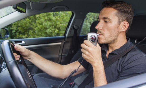 Male driver using breathalyzer
