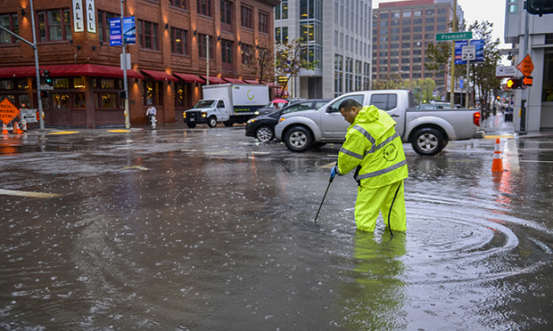 Public works employee cleaning clogged storm drain in San Francisco.