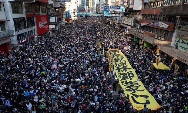 Political unrest can result in property damage, business interruption (BI) and a loss of income for many businesses. Here, demonstrators march through Hong Kong to mark Human Rights Day and press for greater democracy in the city. (Kyle Lam/Bloomberg)