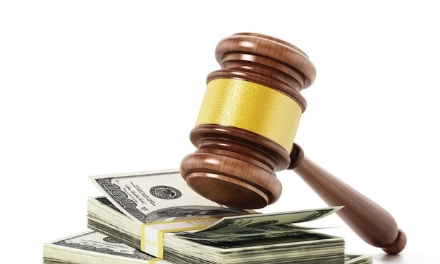 A judge's gavel sits on top of a stack of one-hundred dollar bills. 