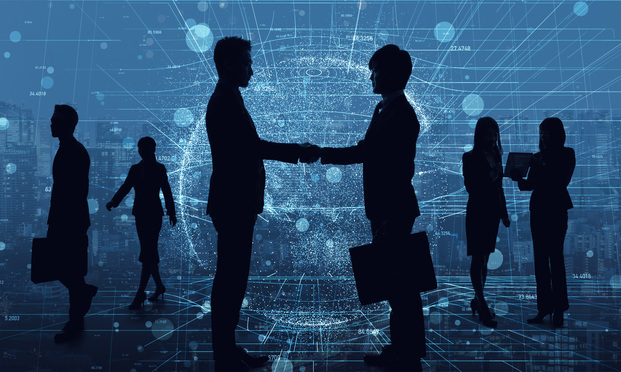 Silhouettes of business people shaking hands in front of a blue, digital backdrop.