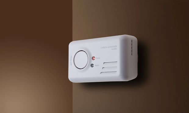A carbon monoxide detector hanging on a brown wall.