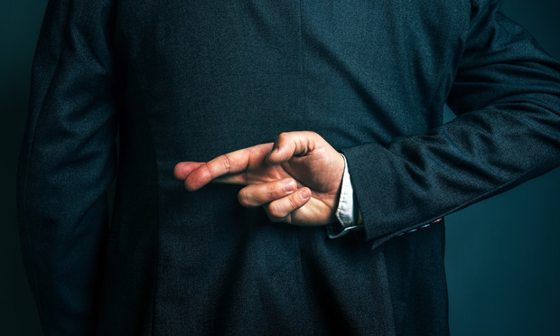 A business man holds his fingers crossed behind his back, indicating that he is lying.