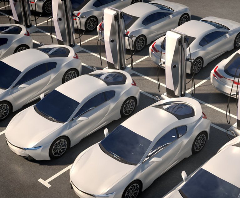 A group of white electric cars hooked up to charging stations.
