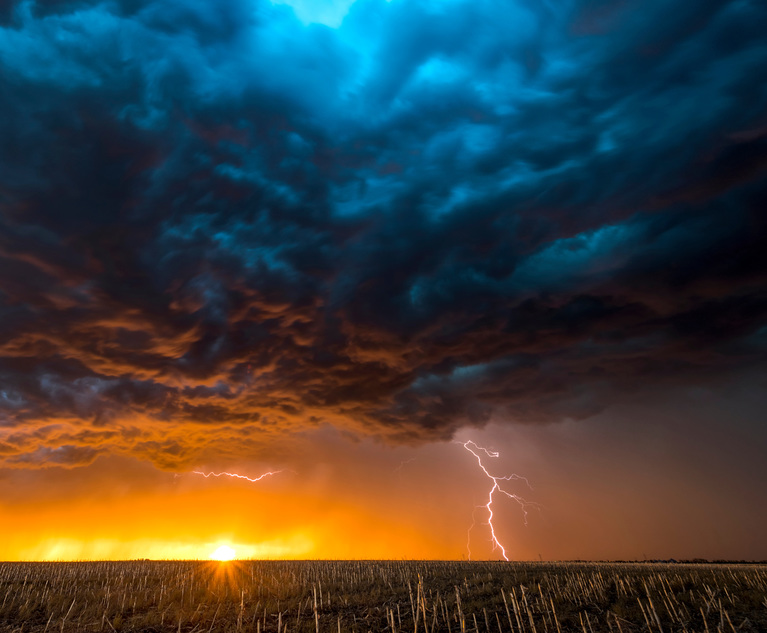 A nighttime, tornadic mezocyclone lightning storm shoots bolt of electricity to the ground and lights up the field and dirt road in Tornado Alley. 