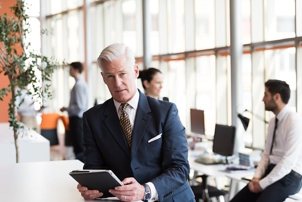 white haired business man looking at tablet in office
