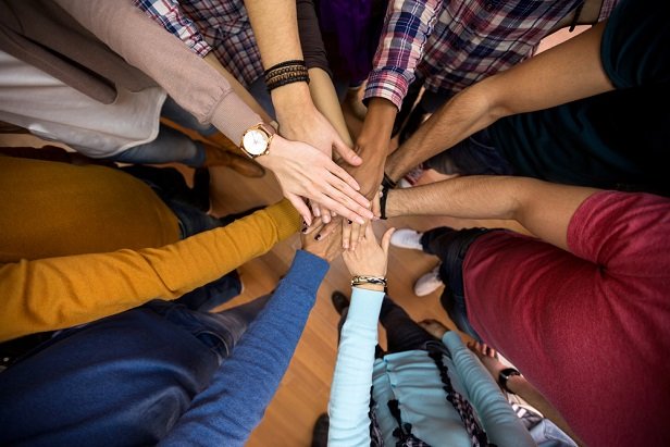 hands of many employees sandwiched on top of each in expression of teamwork