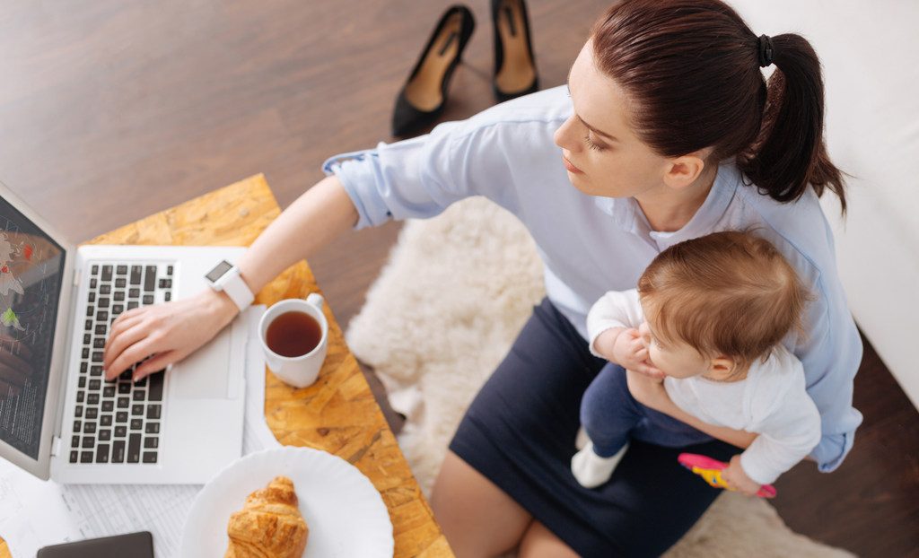Woman holding baby while working