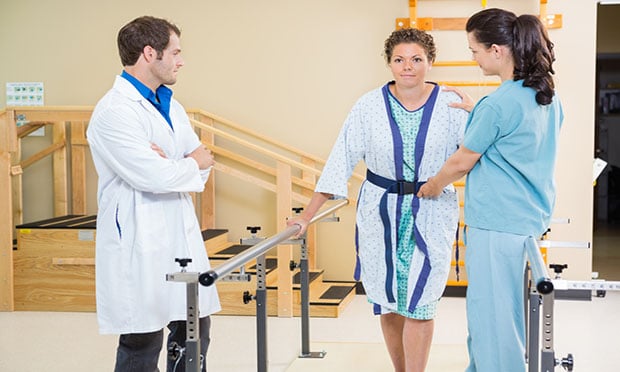 Adult woman patient doing physical rehab with therapist and doctor