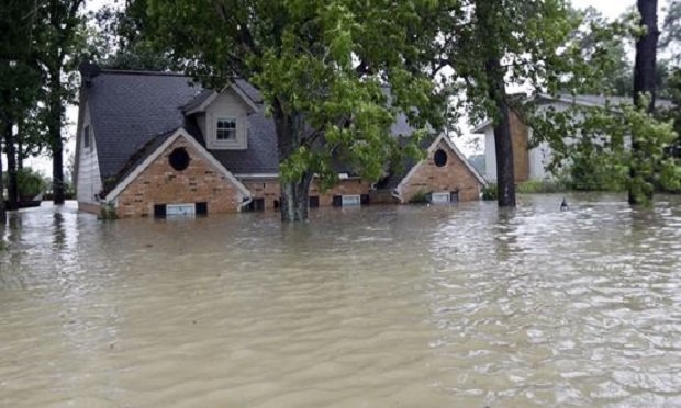 A home is surrounded by floodwaters from Tropical Storm Harvey on Monday, Aug. 28, 2017, in Spring, Texas. Homeowners suffering from Harvey flood damage are more likely to be on the hook for losses than victims of prior storms, a potentially crushing blow to personal finances and neighborhoods along the Gulf Coast. Experts say far too few homeowners have flood insurance, just two of ten living in Harvey's path of destruction. (AP Photo/David J. Phillip)