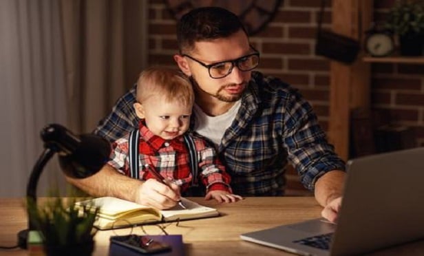 Dad working with son on his lap.