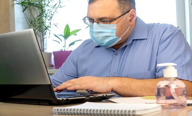 Man in a mask working at his computer.