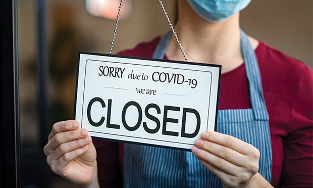Woman hanging a closed sign on a shop door.