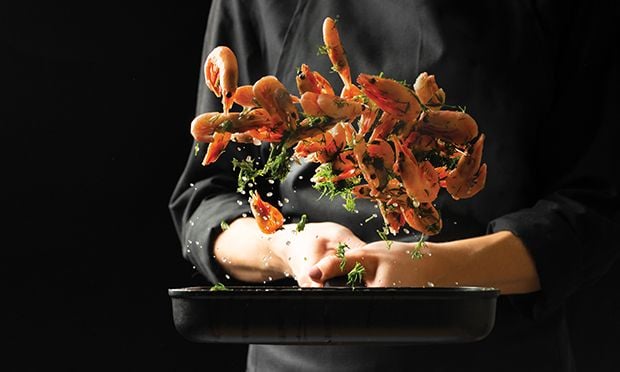 Chef flipping food in a frying pan.