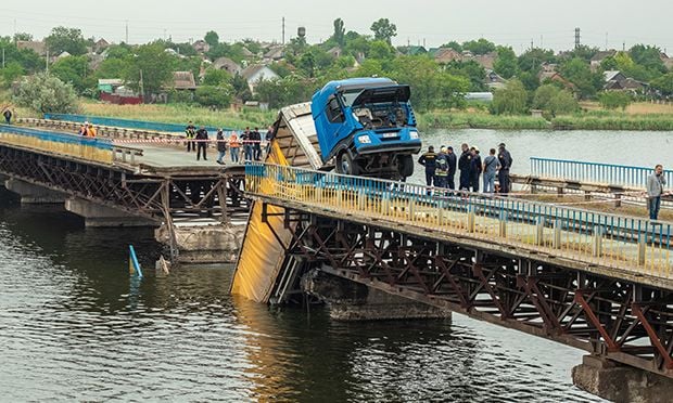 Collapsed bridge with a truck stuck in the middle.