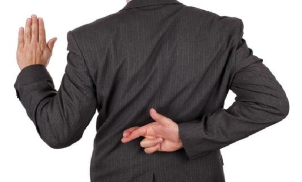 Man raising his hand and crossing his fingers behind his back.