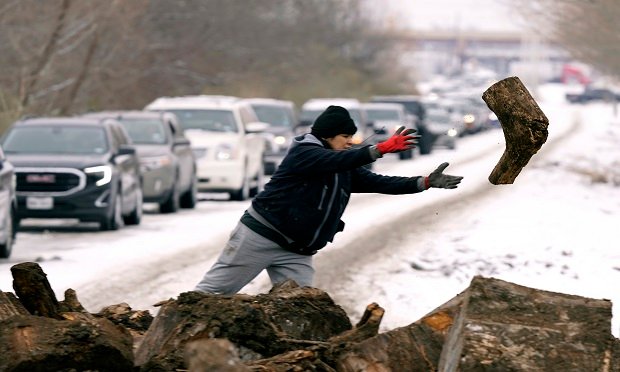 In light of widespread power outages, Texans lined up to collect firewood in Dallas on Wed., Feb. 17, 2021. Groups of thirteen were allowed six minutes to load as much wood as they could carry away from the recycling center. Here, Michelle Terrazas tosses a log off the pile. (AP Photo/LM Otero)