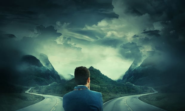 Man pondering which direction to go while standing at crossroads.
