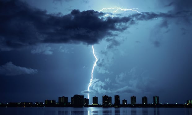 Lightning bolt striking over a city skyline. 