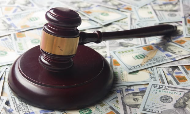 A judge's gavel sits atop a pile of U.S. $100 bills.