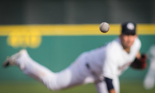Baseball pitcher throwing, ball in foreground.