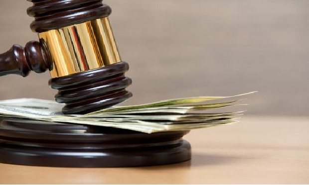 Judge's gavel coming down on a pile of money.