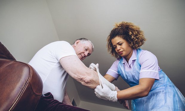 Nurse bandaging a person's arm.