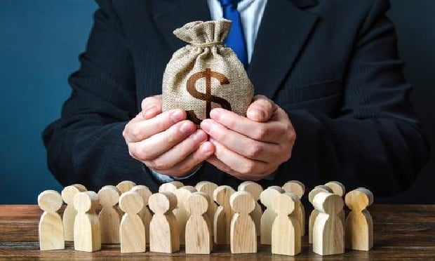 Person counting a bag of money over models of small wooden people.