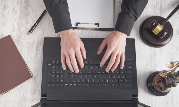 A judge's hands are shown using a laptop. A gavel sits nearby.