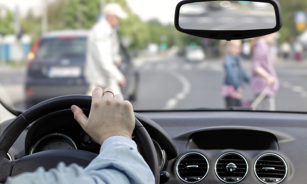 A view from inside of a car as pedestrians cross the road in front of them.