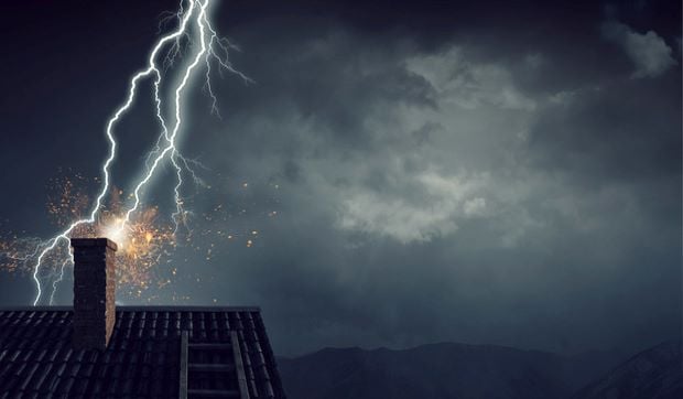 Lightning strikes the chimney of a house.