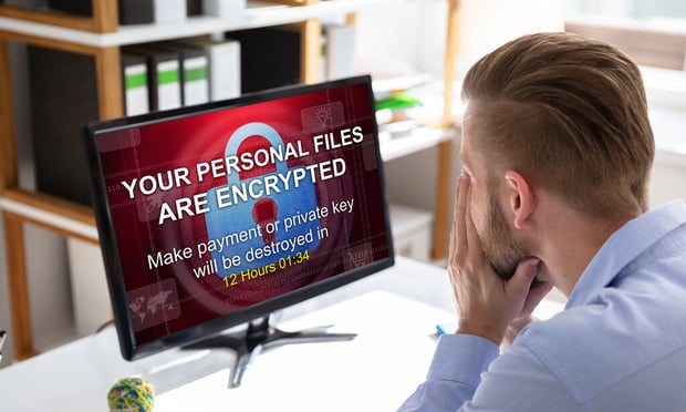 A man stares at a computer with a ransomware alert on the screen.