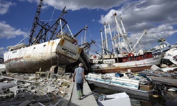 Bruce Hickey, 70, walks along the waterfront, now littered with debris including shrimp boats, in the mobile home park where he and his wife, Kathy, have a winter home on San Carlos Island, Fort Myers Beach, Fla., on Oct. 5, 2022, one week after the passage of Hurricane Ian.
