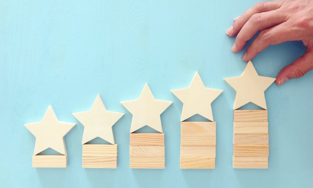 Five wooden stars sit atop wooden block piles of ascending heights. 
