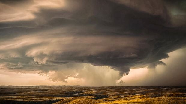 A tornado forms over an open landscape.