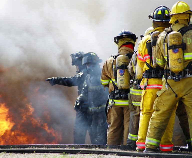 A group of firefighters putting out a fire with a hose.