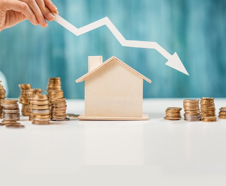 Woman holds an arrow down over model of the house and stack of coins.