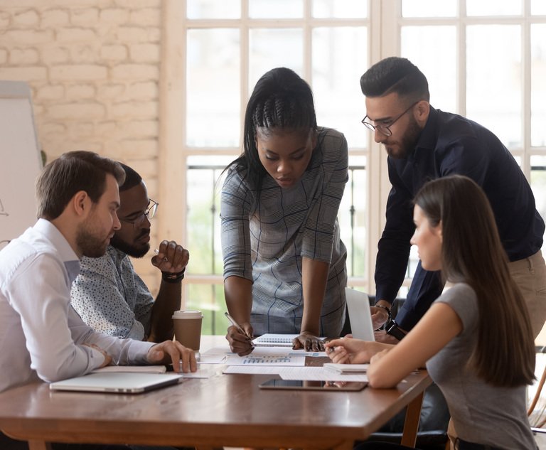A diverse group of coworkers converse at a table.