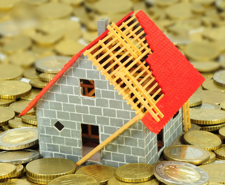 A small, toy house with a broken roof sitting on a bunch of gold coins.