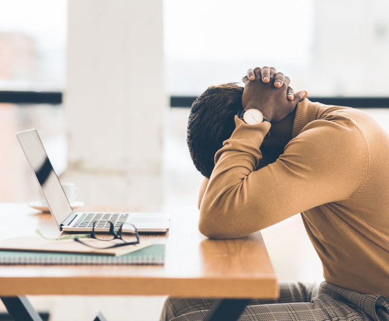 An office worker sitting at a desk with their head down, as if exasperated.