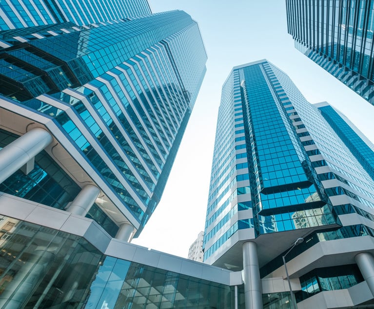 Tall office buildings in a city, photographed from below.