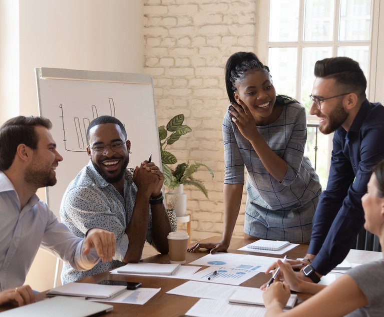 A group of happy office employees chatting around a table.