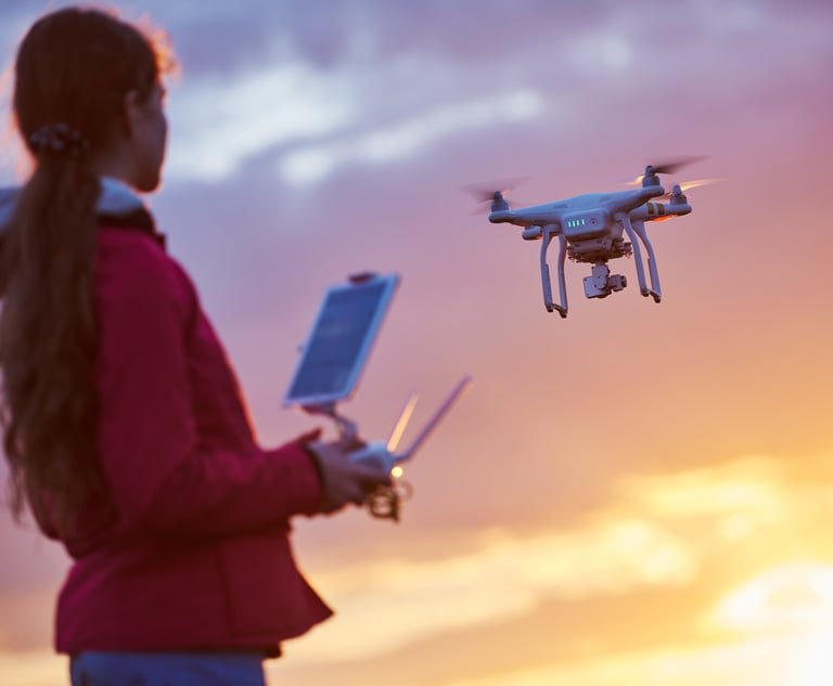 A woman looks up into the sky as she flies a drone.