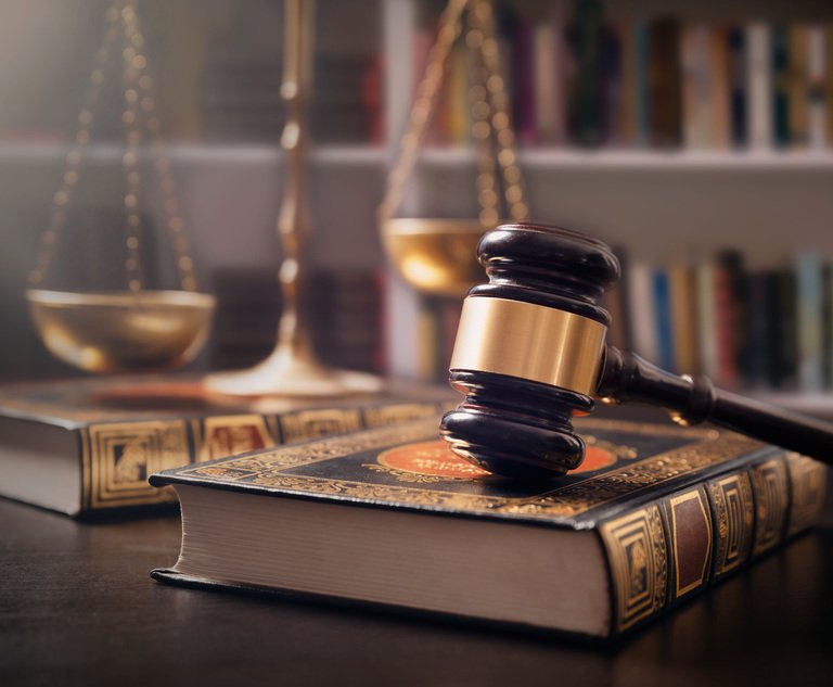 A judge's gavel and scales sit on a desk with some books.
