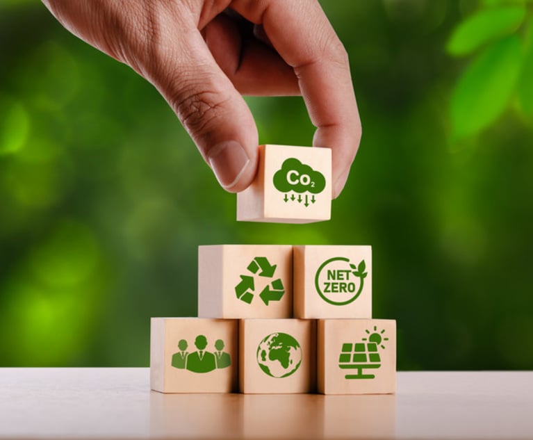A hand stacking wooden blocks with climate related imagery on them.
