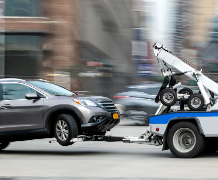 A tow truck towing a car through city streets.