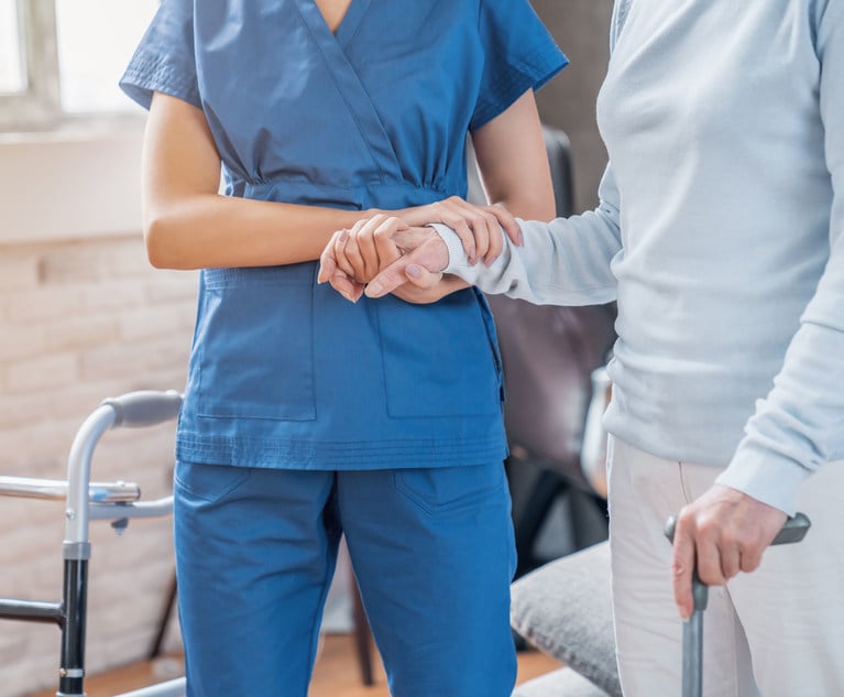 A nurse helps an elderly person who is using a cane.