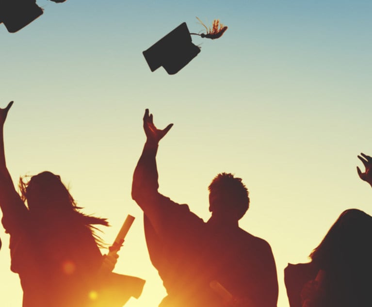 Silhouetted graduates tossing their caps 