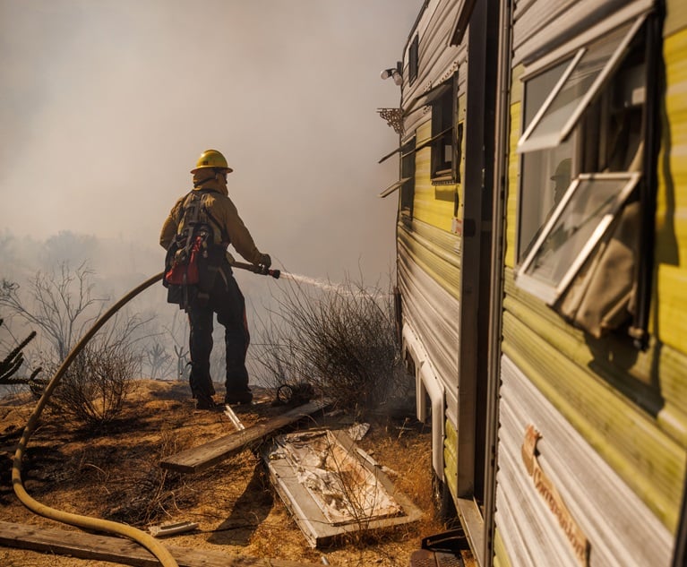 A firefighter douses flames while battling the 2023 Highland Fire in Aguanga, Calif. (Credit:  Ethan Swope/Bloomberg)